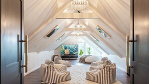 An attic room with a sloped ceiling, a large TV, and striped bean bag chairs. - Luna Cove: Premier Hudson Valley Getaway (South Cairo)