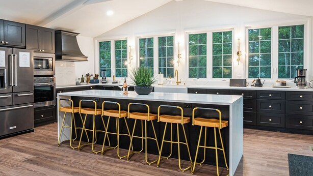 A modern kitchen with a large island, bar stools, and a view of the outdoors through large windows. - Luna Cove: Premier Hudson Valley Getaway (South Cairo)