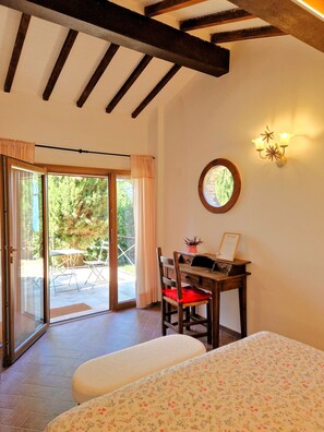 A room with a wooden ceiling, a dining table with chairs, a small potted plant, a wall-mounted mirror, and a sliding glass door leading to an outdoor area with a table and chairs.