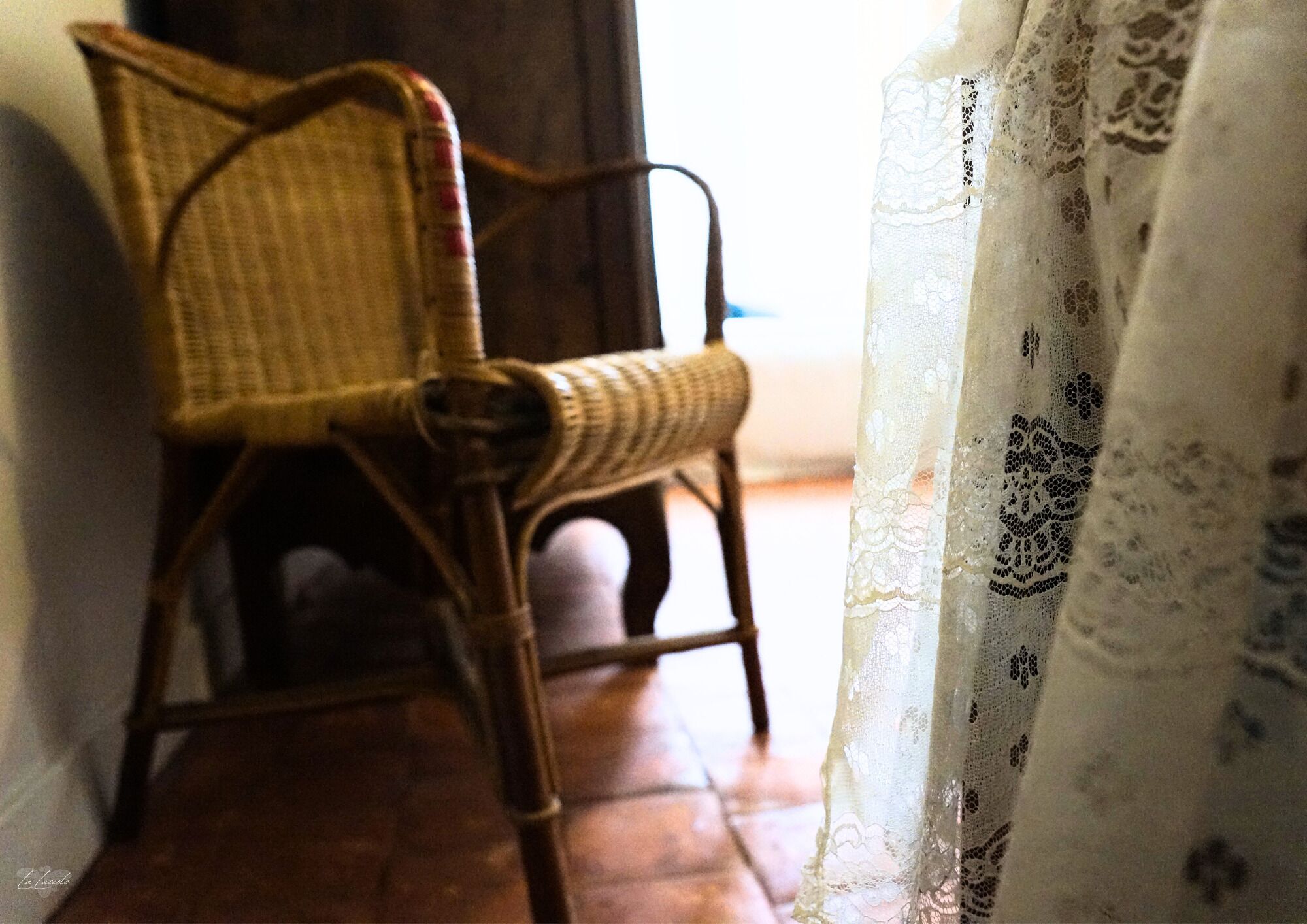 A wicker chair in a room with a patterned curtain.