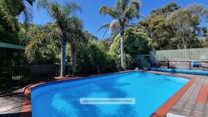 A swimming pool surrounded by trees and a wooden fence.