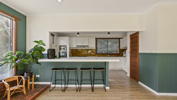 A compact kitchen with a central island, bar stools, a microwave, and a large window.