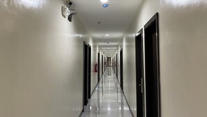 A long, narrow hallway with a shiny, reflective floor and white walls.