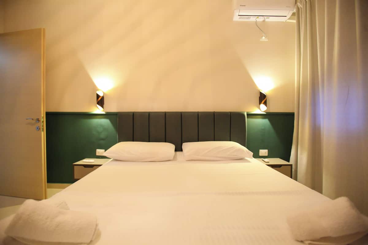 A hotel room with a large bed, two bedside tables, and a headboard.