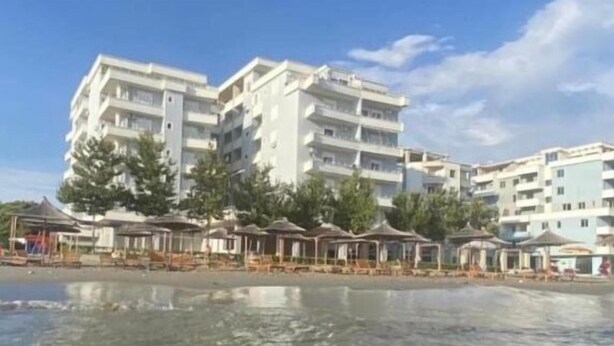 Un hotel sulla spiaggia con diversi piani, zone relax all'aperto e una piscina.