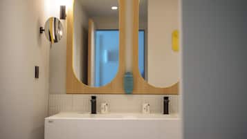 Un bagno moderno con doppio lavabo, due specchi fissati alla parete e un lampadario sopra lo specchio.