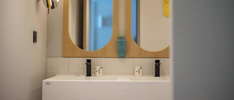 A modern bathroom with a double sink, two wall-mounted mirrors, and a light fixture above the mirror.