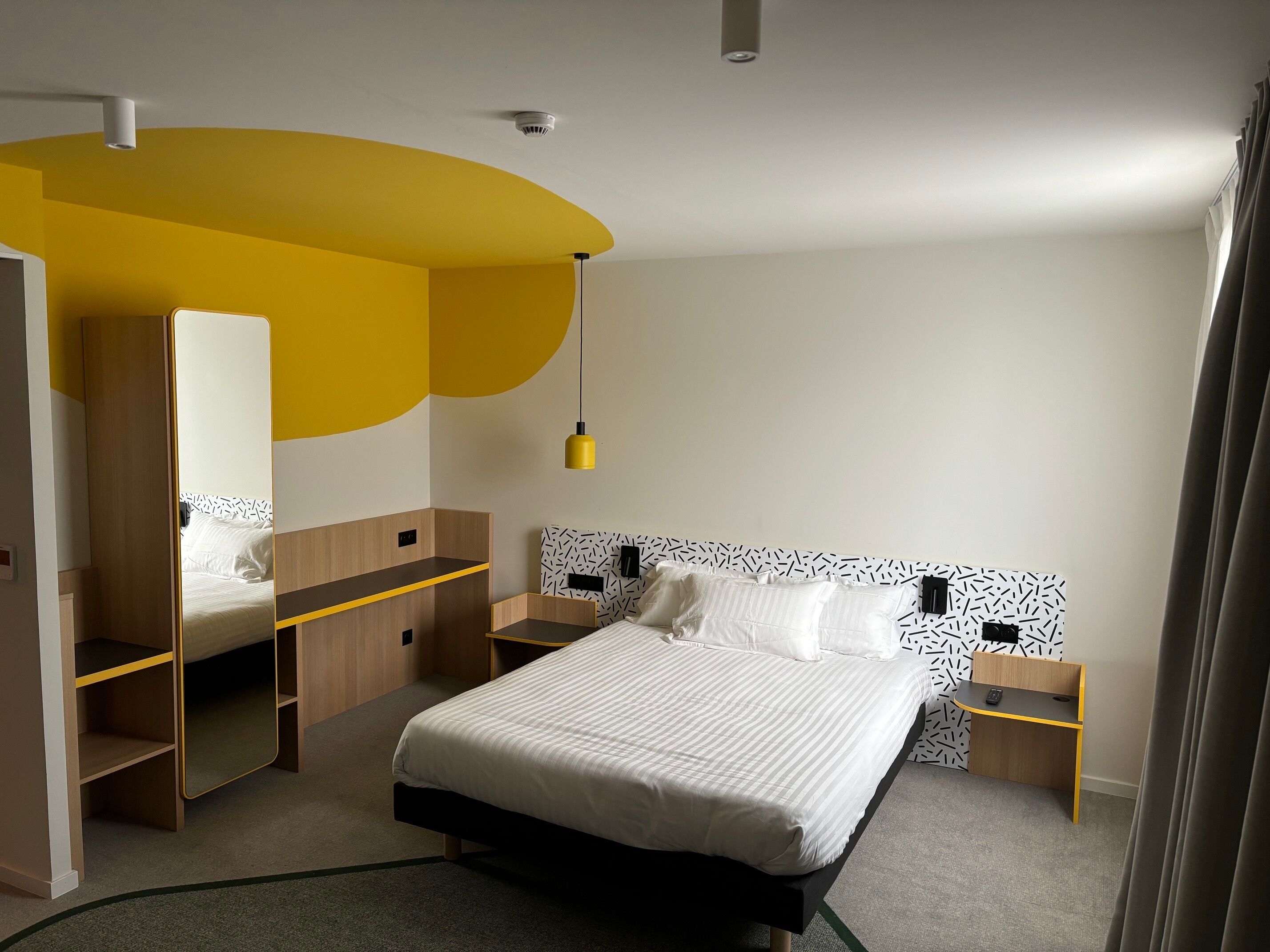 A modern bedroom with a bed, bedside tables, a wardrobe, and a mirror.