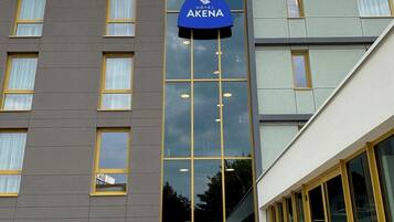 A modern hotel building with a prominent 'Hotel Akena' sign, large windows, and a flat facade.
