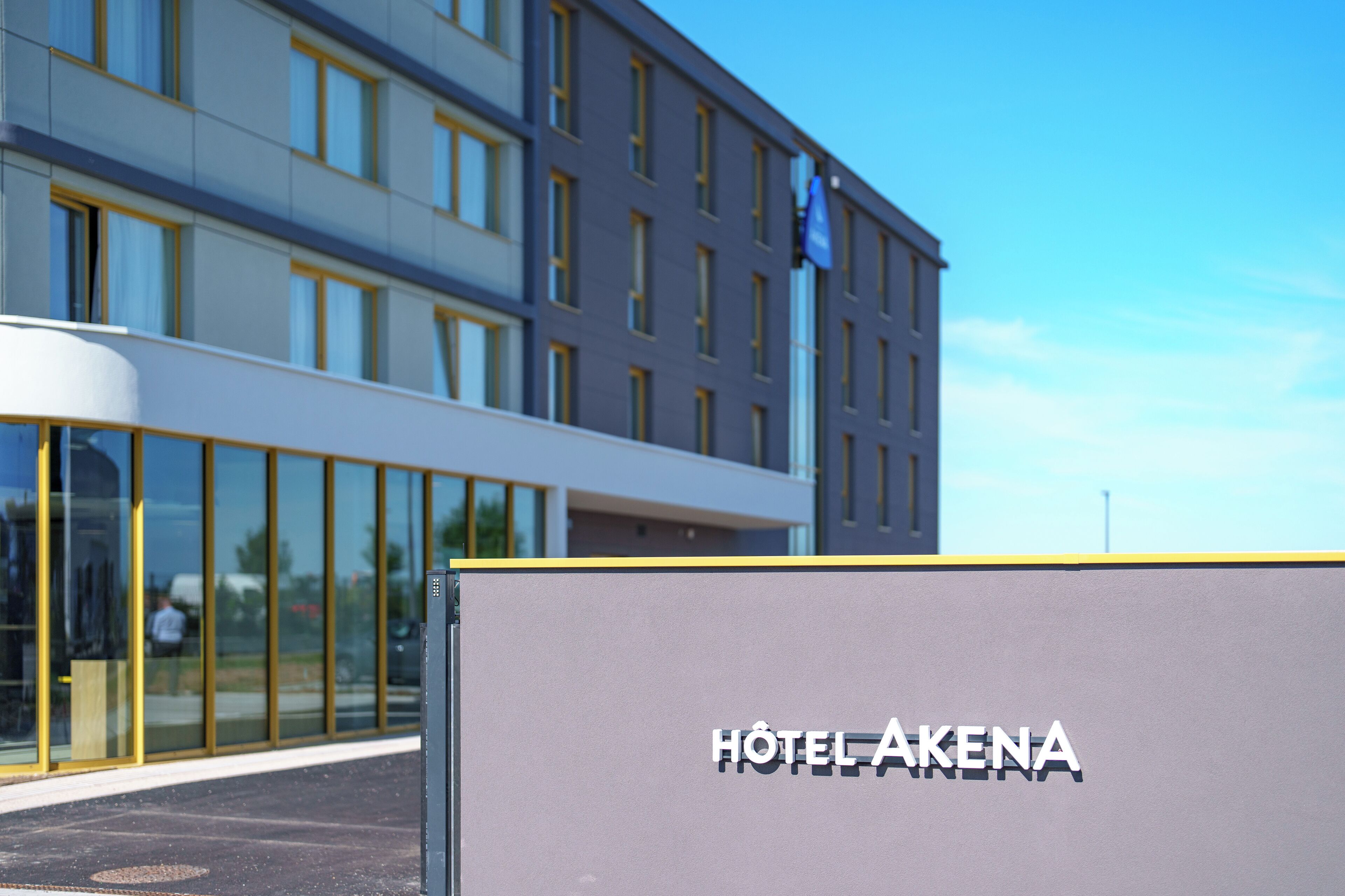 A modern hotel building with a sign reading "HOTEL AKENA".