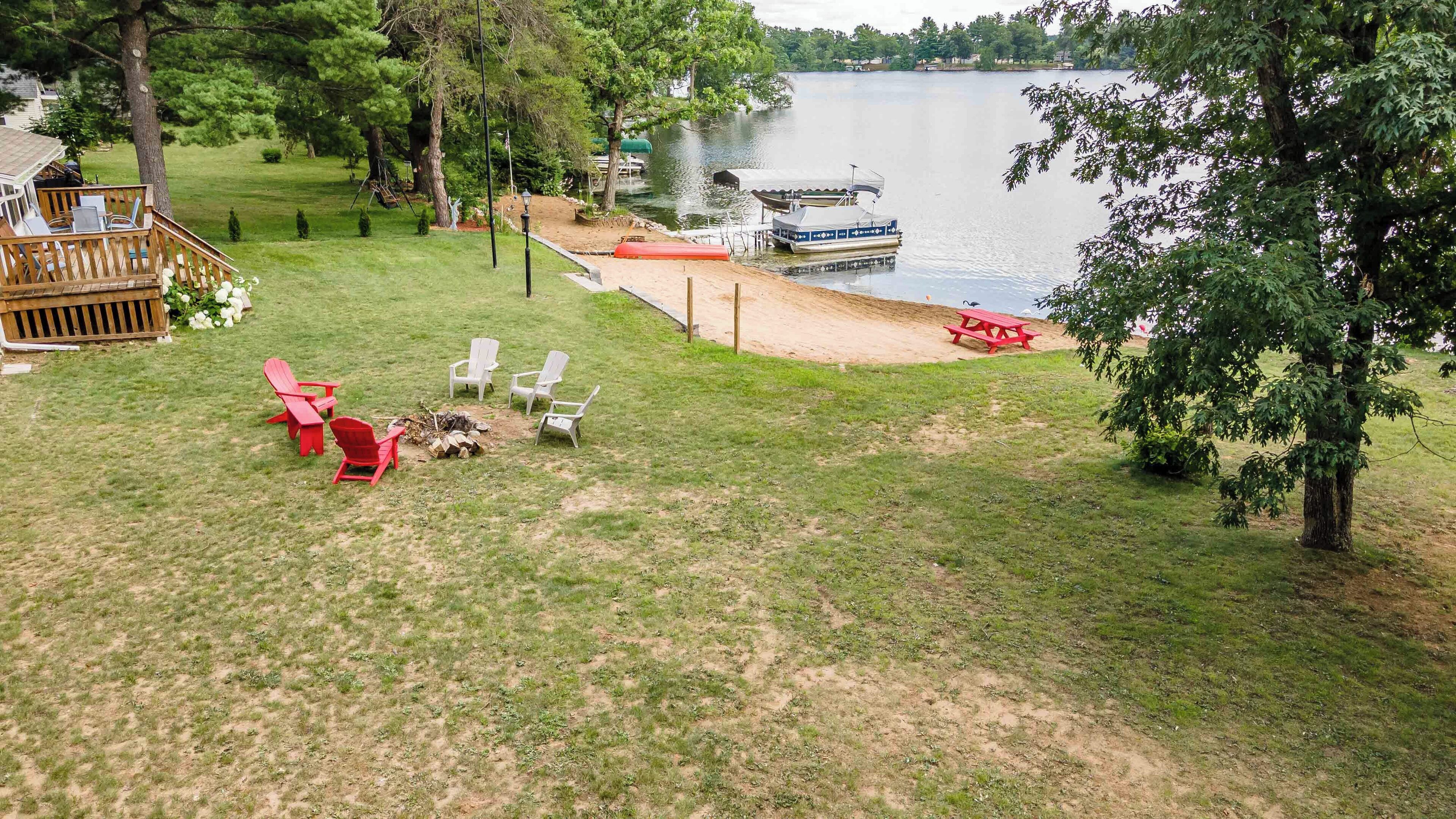 A lakeside deck with outdoor seating, a dock, and a boat.