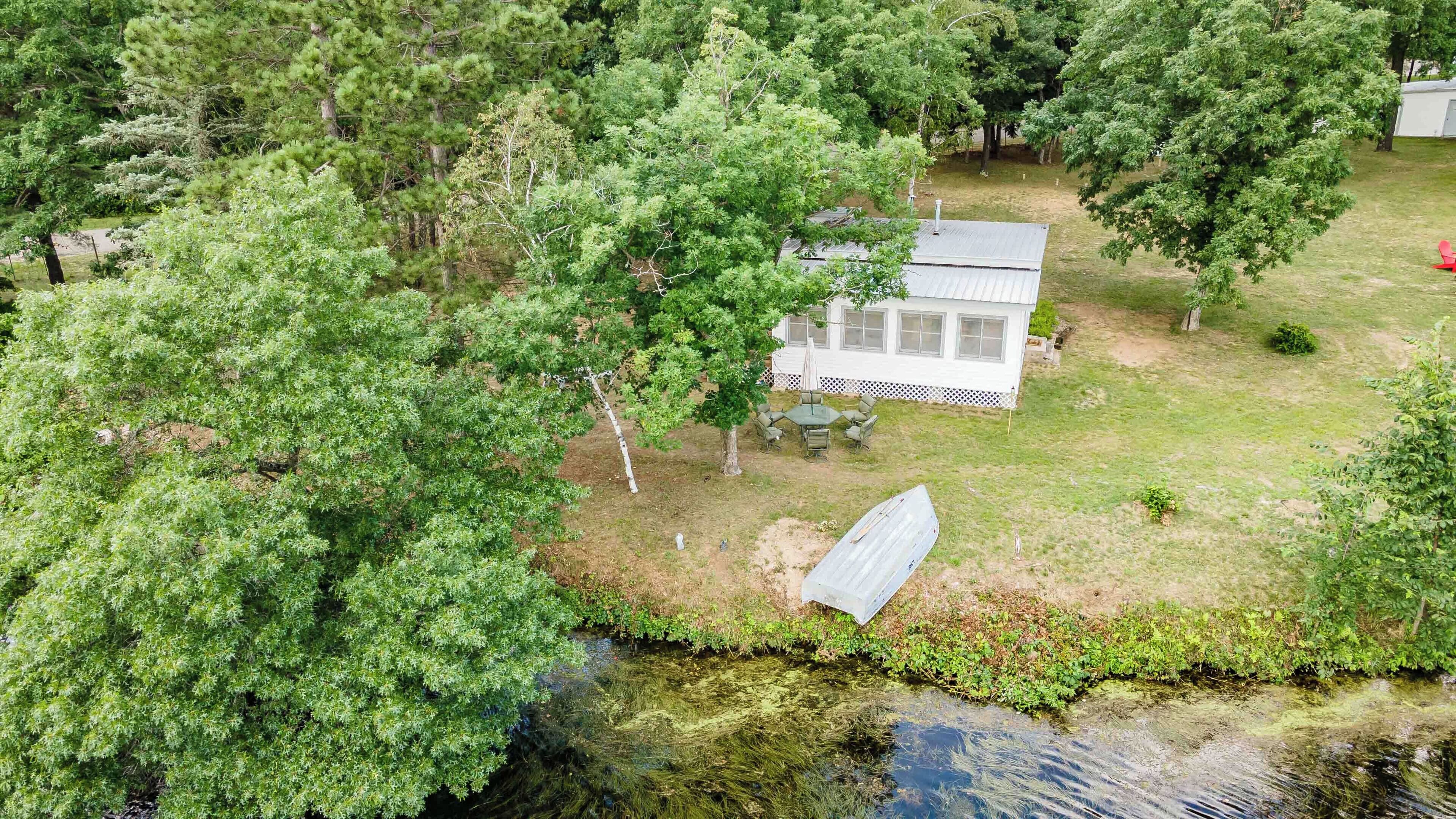 A house with a fenced yard, a small dock, and a pond.