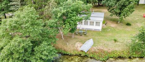 A house with a fenced yard, a small dock, and a pond.