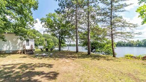Un camping con una cabaña pequeña, mesas de picnic y vista al lago.