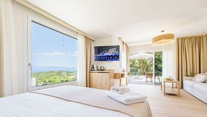 Habitación de hotel con una cama grande, televisión, balcón con una silla y un sofá.
