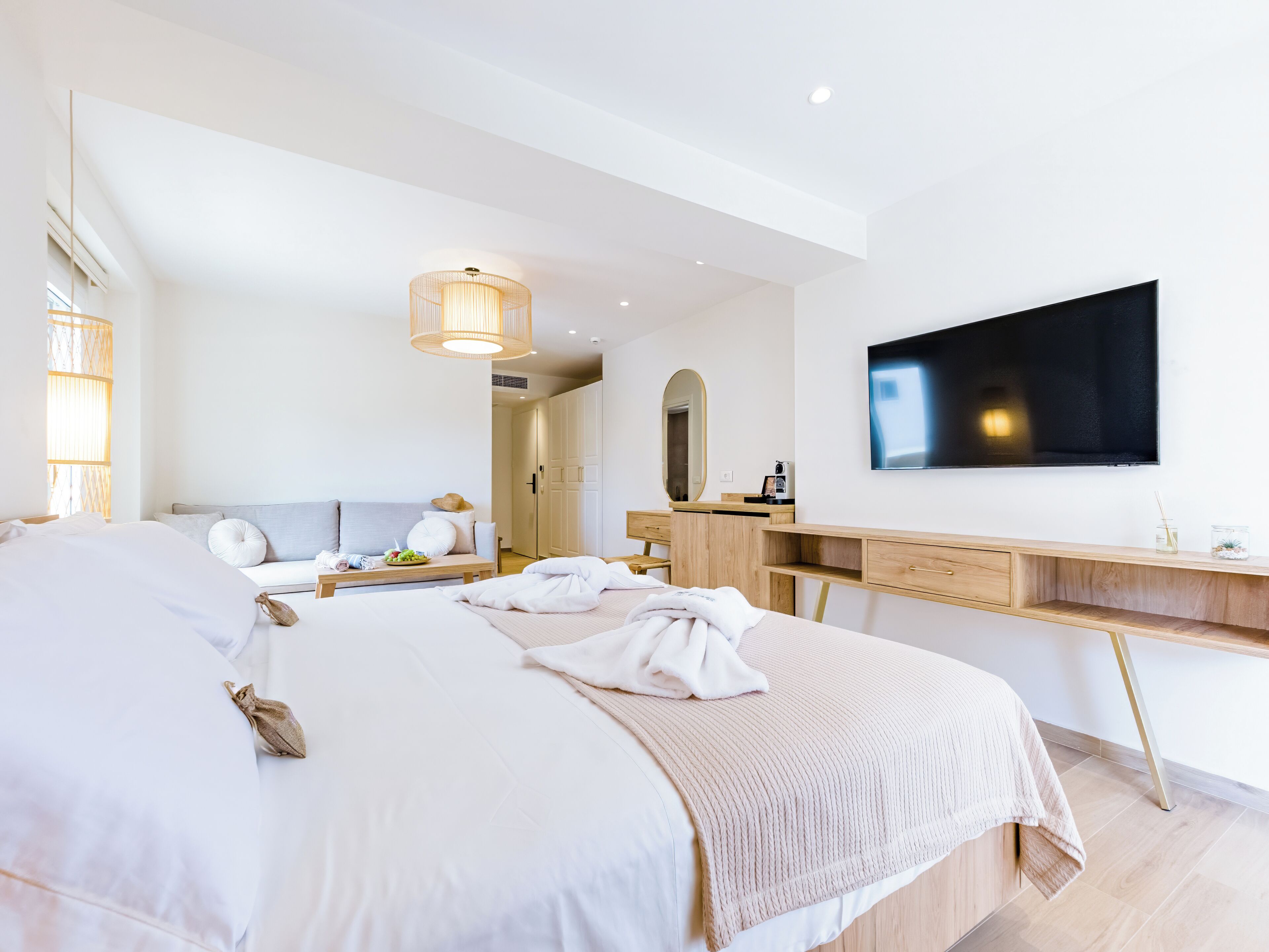 Una habitación de hotel moderna con una cama grande, un escritorio y un televisor montado en la pared.