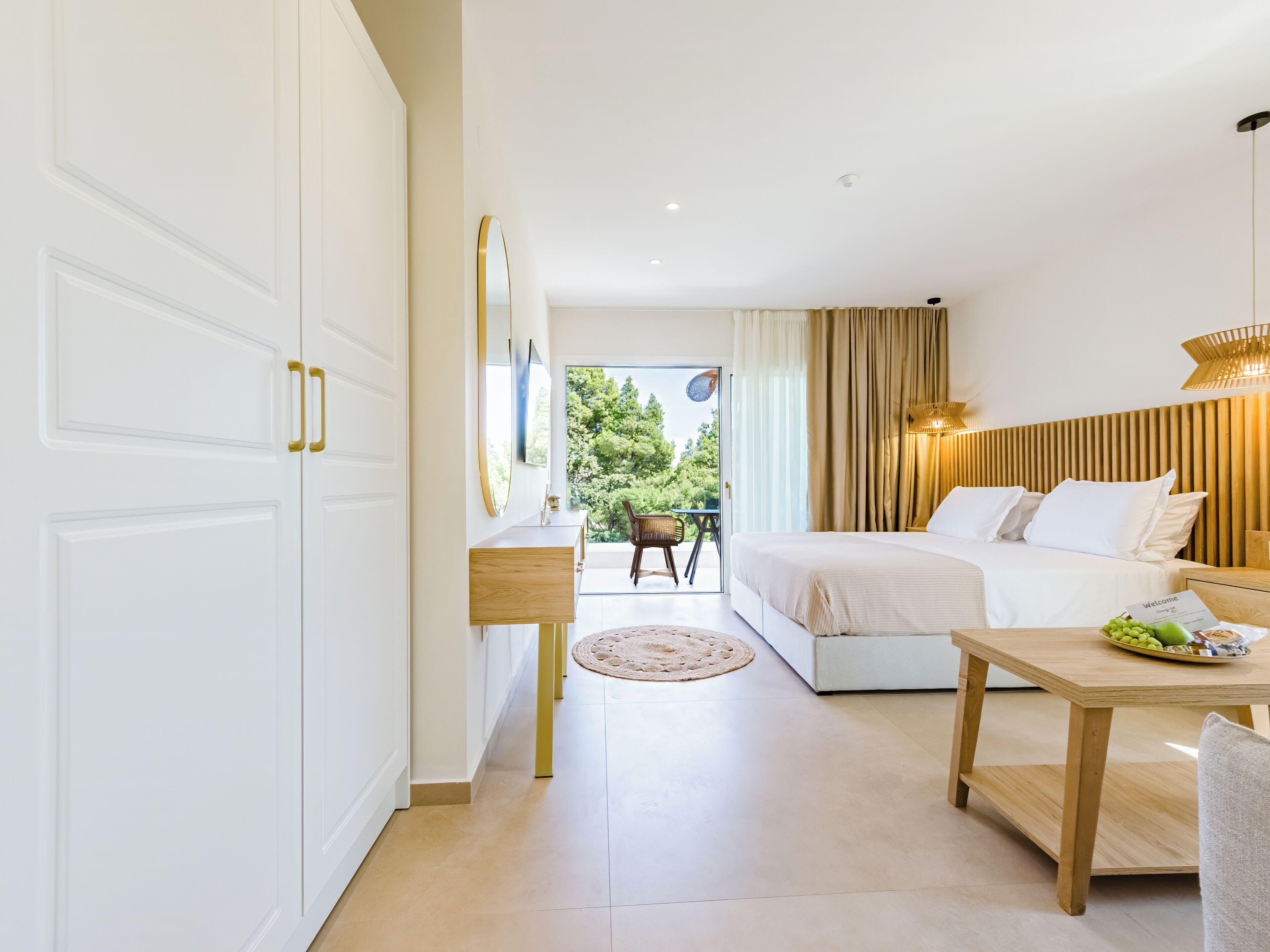 A modern hotel room with a bed, bedside table, and a view of the outdoors.