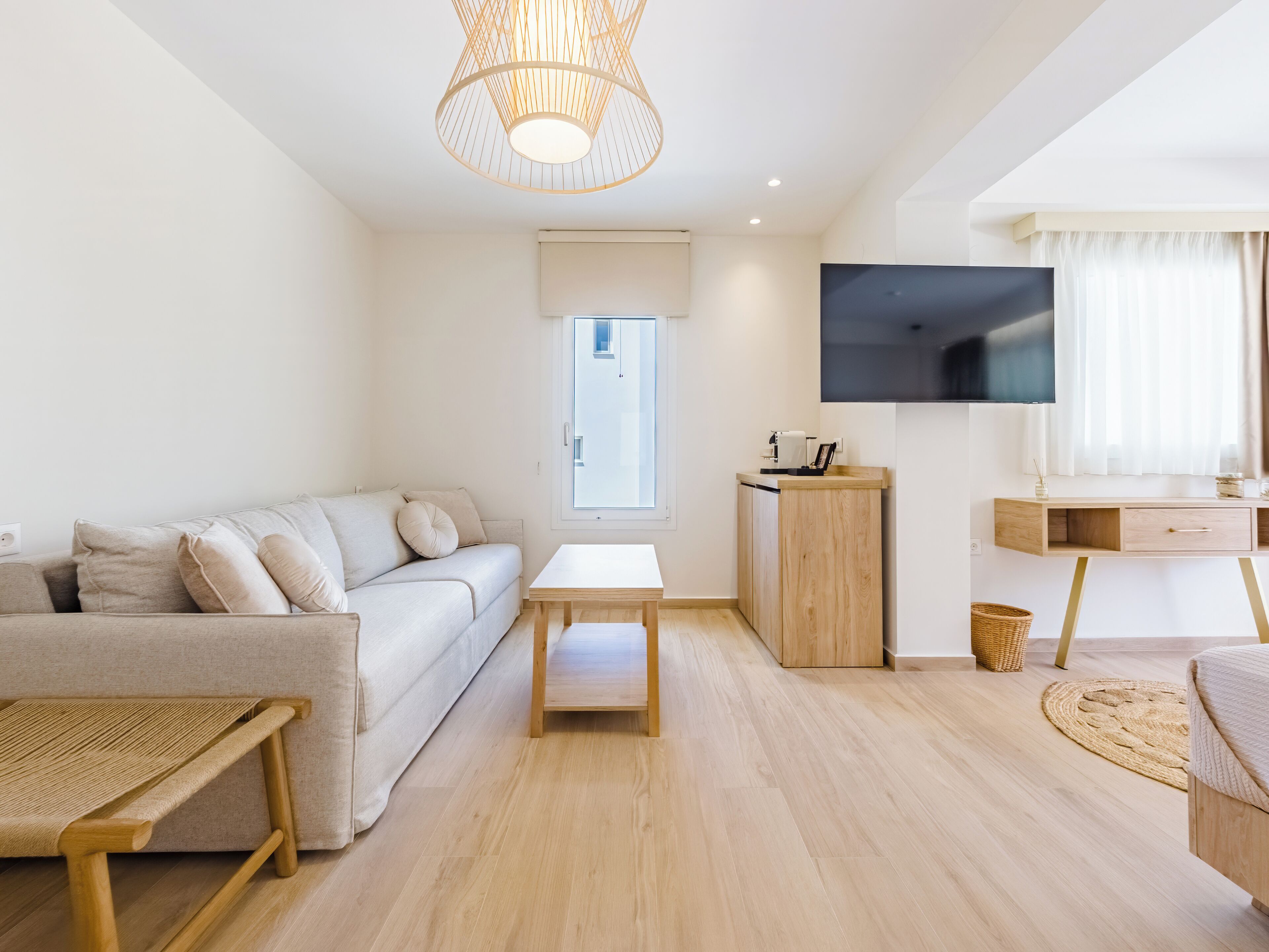 Una sala de estar moderna con un sofá, una mesita, un televisor y un mueble de madera.