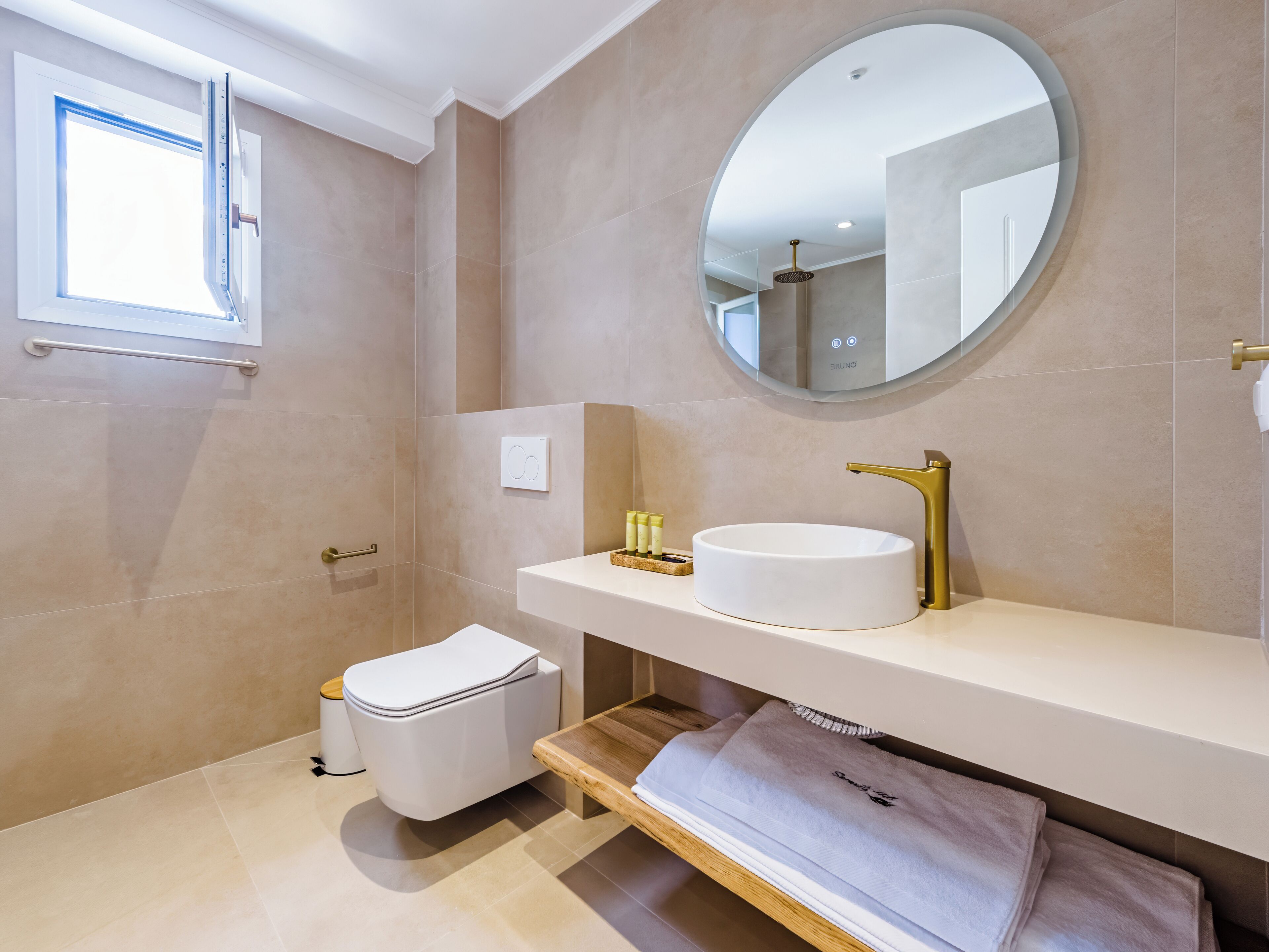 Un baño moderno con inodoro, lavamanos y espejo.