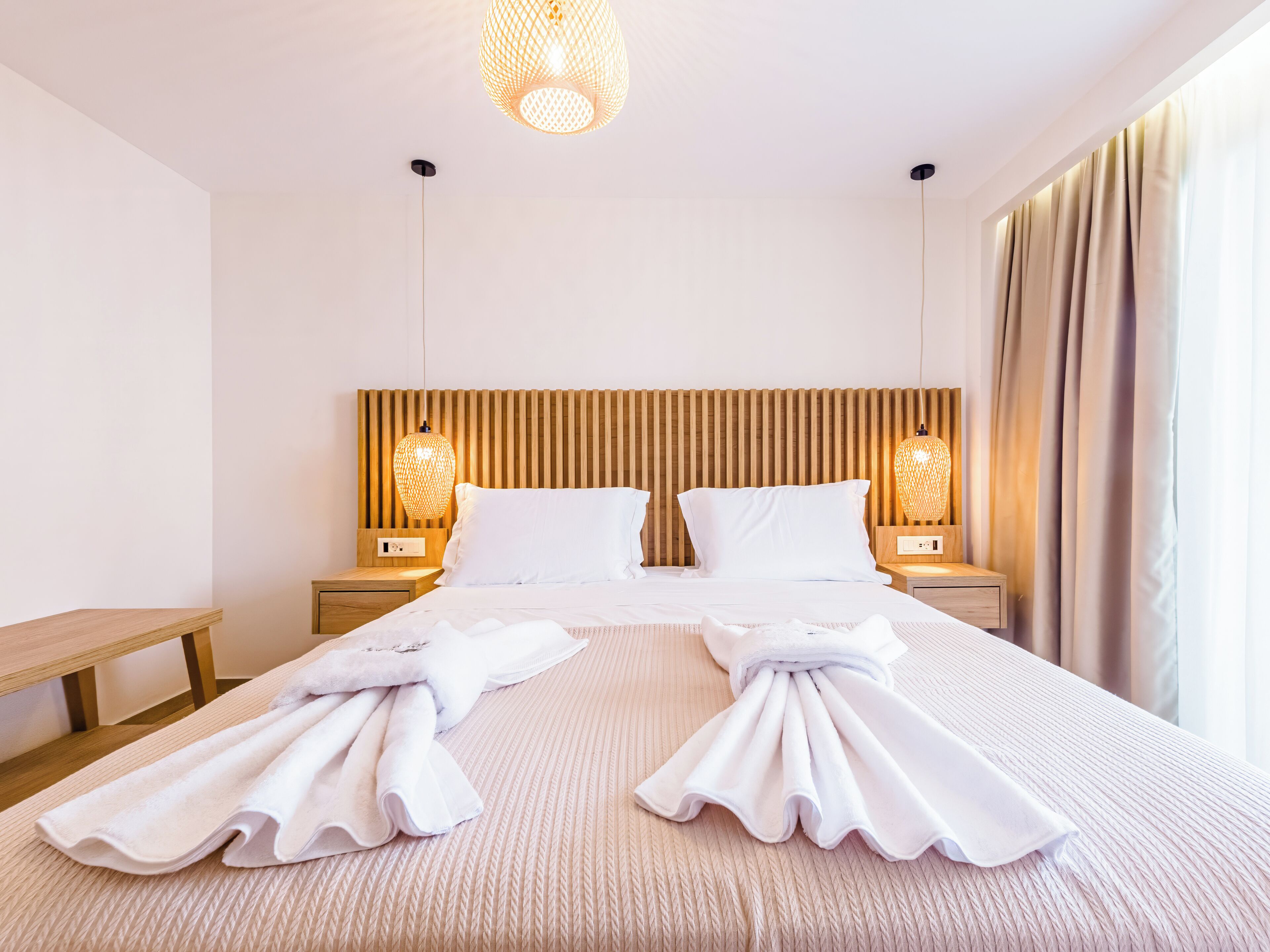 Ein Hotelzimmer mit einem großen Bett, zwei Nachttischen, einem Holzkopfende und zwei Wandlampen.