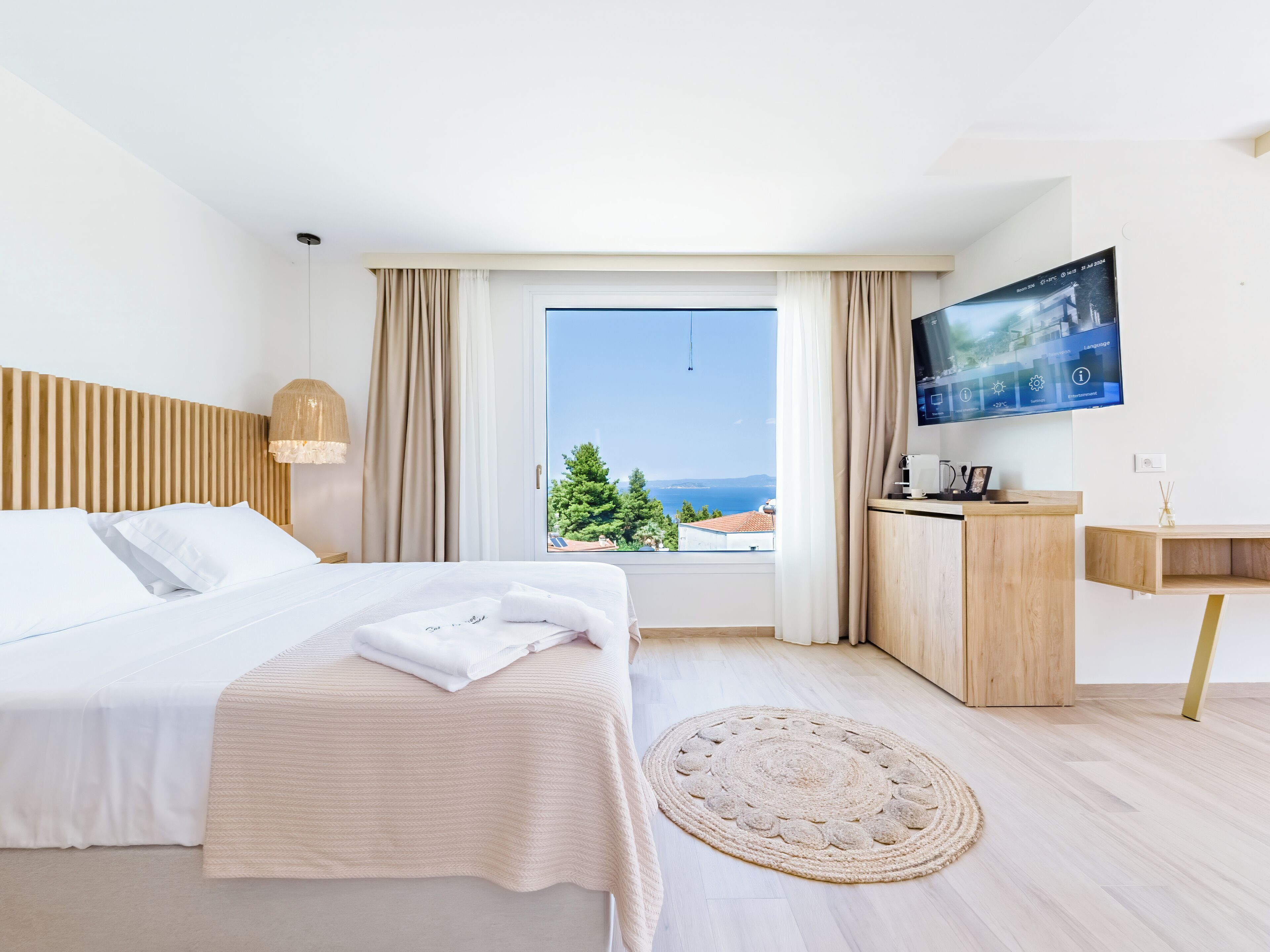 Una habitación de hotel con cama, escritorio, televisor y vista al mar.