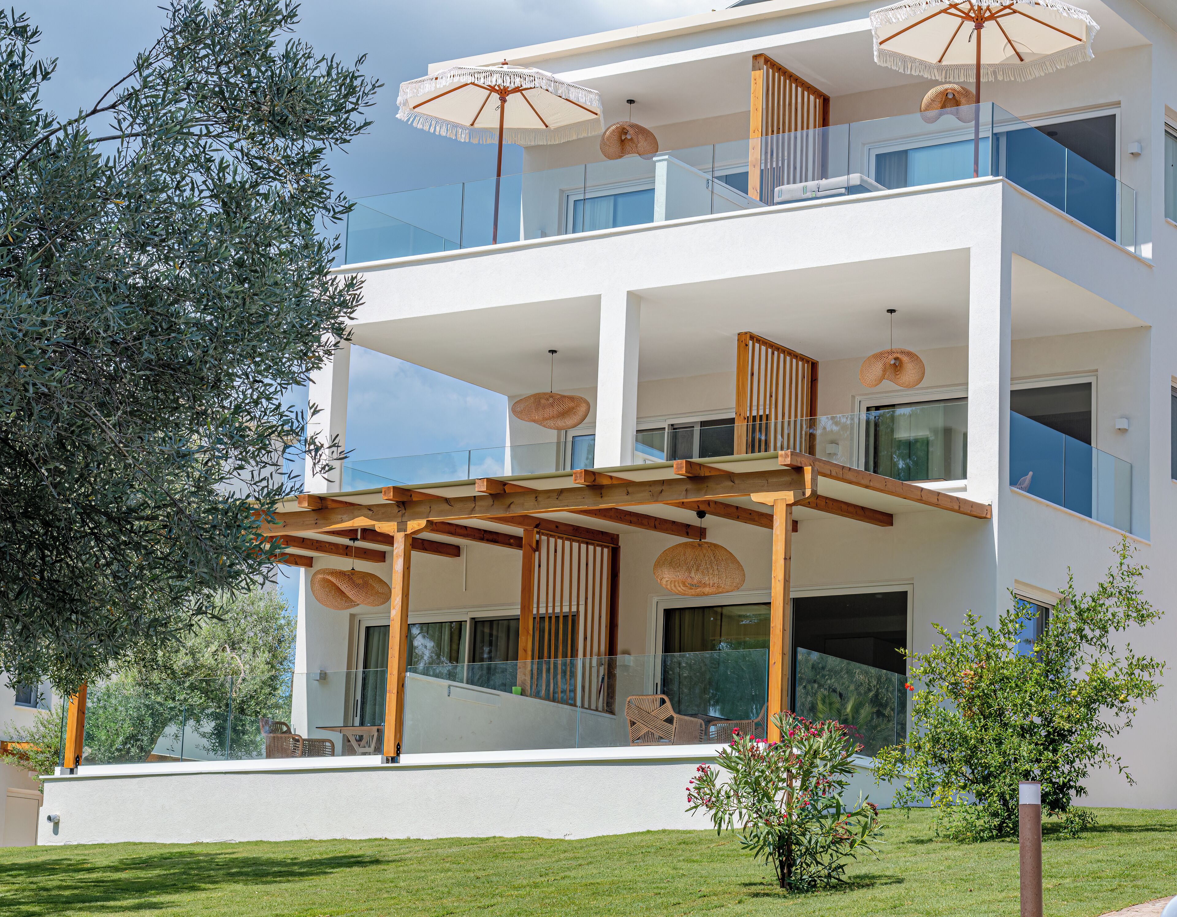 A modern multi-story building with balconies, outdoor seating, and a well-maintained lawn.