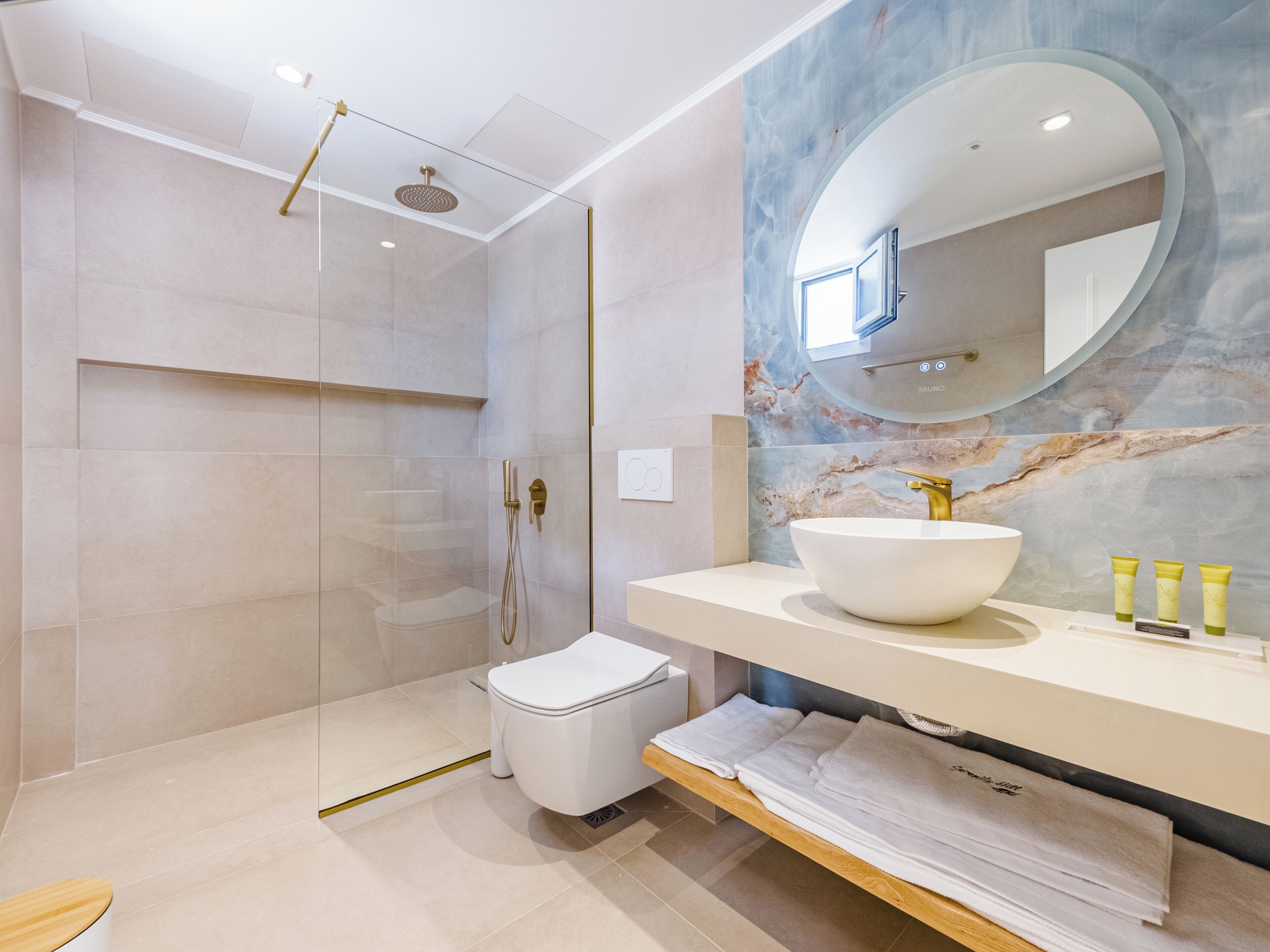 A modern bathroom with a glass-enclosed shower, a white toilet, a marble vanity with a large sink, and a mirror above the vanity.