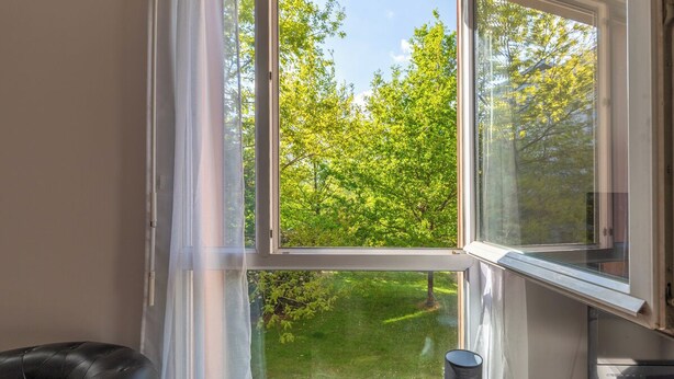 Een kamer met een groot raam dat uitzicht biedt op een groen landschap.