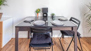 Een eettafel met vier stoelen, een koffiezetapparaat en een kleine potplant.