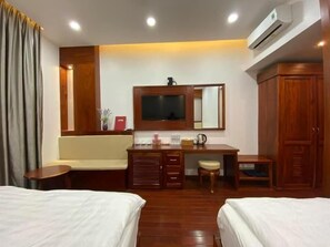 A hotel room with two beds, a wooden desk with a mirror, a television, and a wardrobe. - Pandora Hotel CT by Bay Luxury (Can Tho)