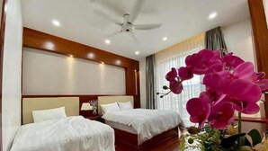 Habitación de hotel con dos camas, ventilador de techo y una orquídea en maceta.