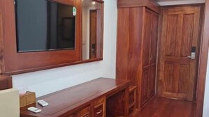 Una habitación con un escritorio de madera, un espejo, un banco y un taburete pequeño.