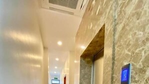 Un pasillo moderno de hotel con pared de mármol y un ascensor.