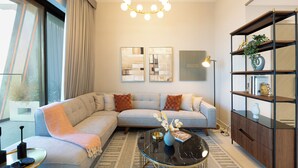 A modern living room with a sectional sofa, a glass coffee table, and a bookshelf. - Spacious 2BR Canal View - Heart of B Bay (Dubai)