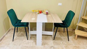 Ein Essbereich mit einem Holztisch und zwei bequemen, grünen Sesseln.