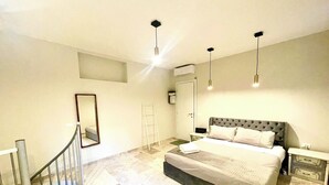 Ein Schlafzimmer mit einem Bett, einem Nachttisch, einem Spiegel, einer Leiter und einer Treppe.