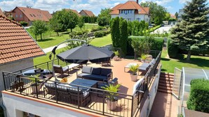A balcony with outdoor furniture, a grill, and a view of a residential area. - Villa Nova Hévíz - Apartment 7 top floor (Hévíz)