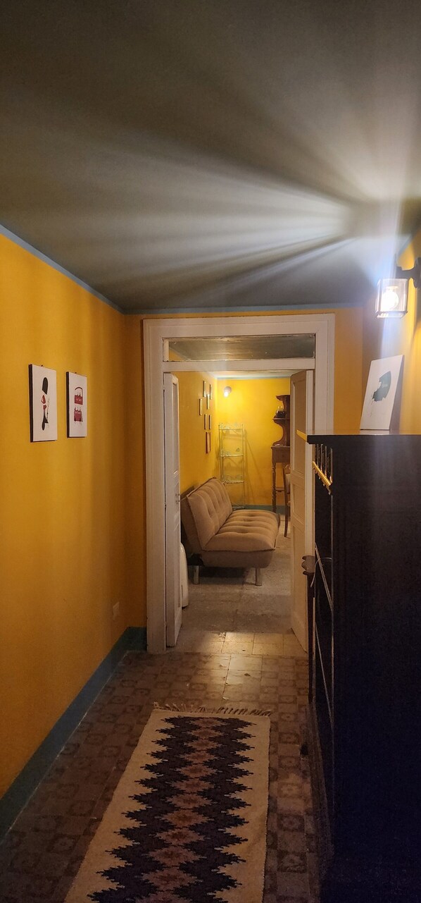A hallway with a patterned rug, a sofa in the background, and framed pictures on the walls. - Noble palace sky view in the mountains, near the historic center of Erice (Erice)