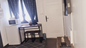 Et kompakt køkken med mikrobølgeovn, et lille bord og en skraldespand.