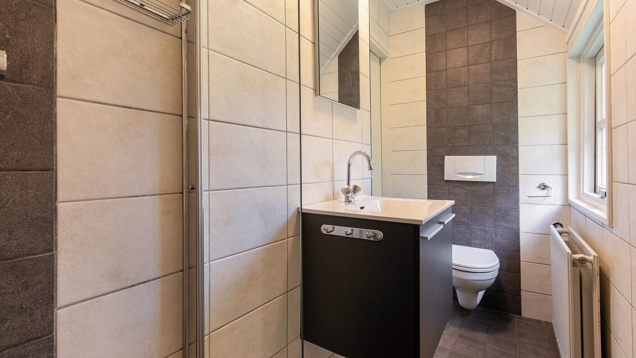 A compact bathroom with a shower, a sink, and a toilet.