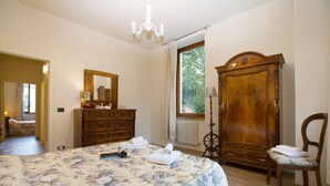 Ein Schlafzimmer mit einem großen Bett, einem hölzernen Schminktisch, einem Sessel und einem Kleiderschrank.