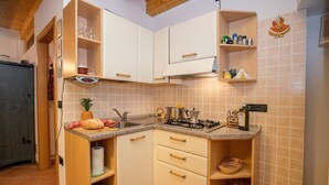 Uma cozinha compacta com armários brancos, fogão a gás e diversos utensílios.