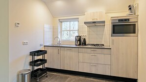 A compact kitchen with a built-in oven, a coffee maker, and a window. - Ground-floor bungalow for 4 people (Herpen)
