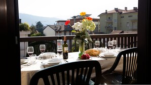 A dining table set for two with a view of buildings and mountains in the background. - Appartamento Amy in Riva del Garda (Riva del Garda)
