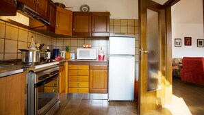A kitchen with wooden cabinets, a stove, a microwave, and a refrigerator. - Appartamento Amy in Riva del Garda (Riva del Garda)