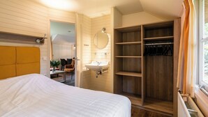 Ein Schlafzimmer mit Bett, Nachttisch, Spiegel, Waschbecken und einem Holzschrank.