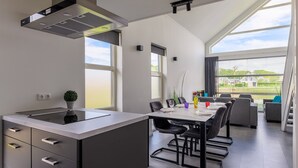 Una cucina moderna con isola centrale, zona pranzo con tavolo e sedie, e ampie finestre con vista sull'esterno.