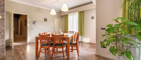 Un comedor con una mesa y sillas de madera, una lámpara colgante y una planta verde.