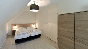 A bedroom with a bed, bedside tables, a wardrobe, and a ceiling light. - Bungalow for 4 persons (Steendam)