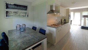 A modern kitchen with a dining table, chairs, and a stove. - Bungalow for 4 persons (Steendam)